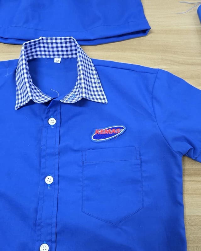 Baju biru dengan contoh sulaman logo pada dada